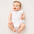Baby in a white bubble with hand embroidered bow and rosettes design on a white quilt