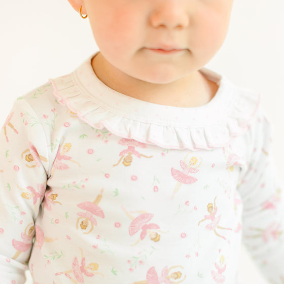 Child wearing a long-sleeve pajama with ballerina design on a white background