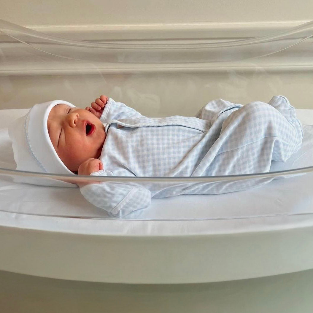 newborn boy in hospital bassinet wearing minicheck footie by magnolia baby in light blue
