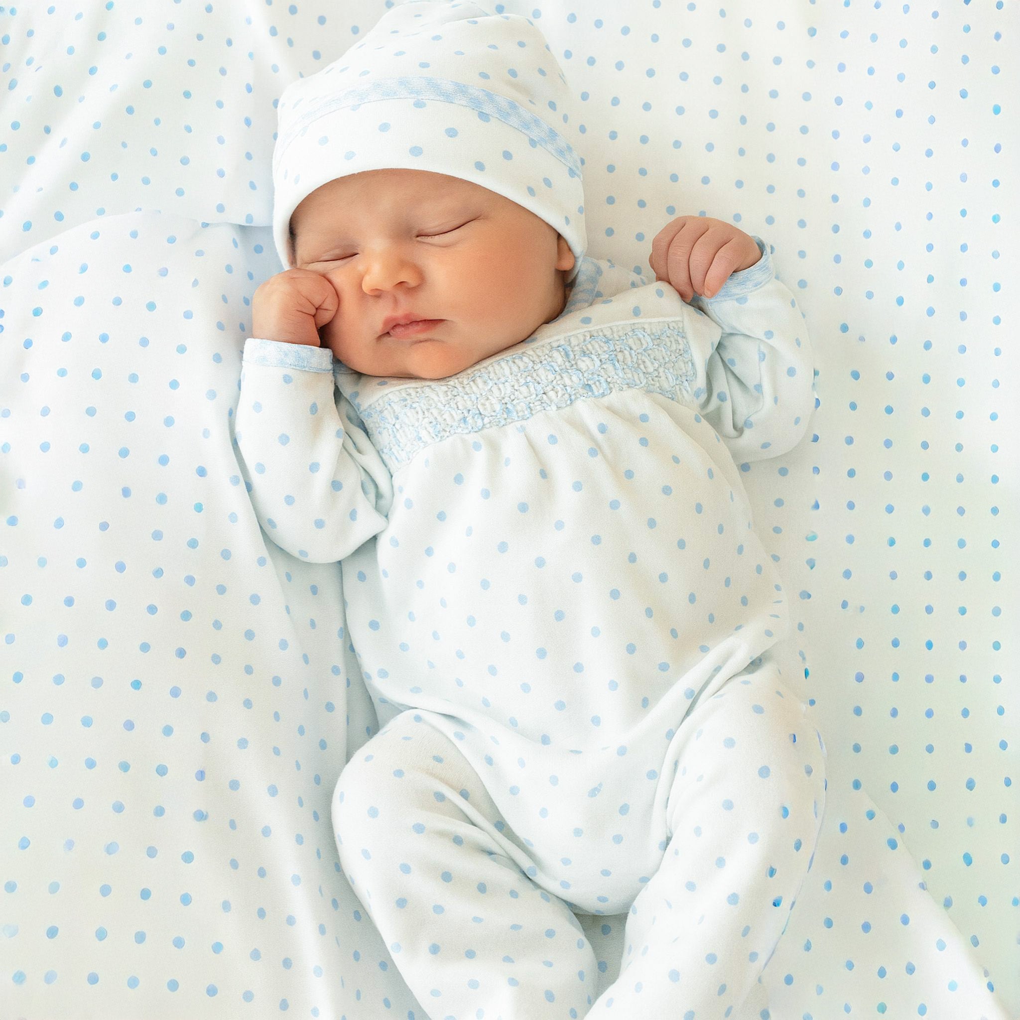 Smocked blue dot footed sleeper with snap closures and gingham trim