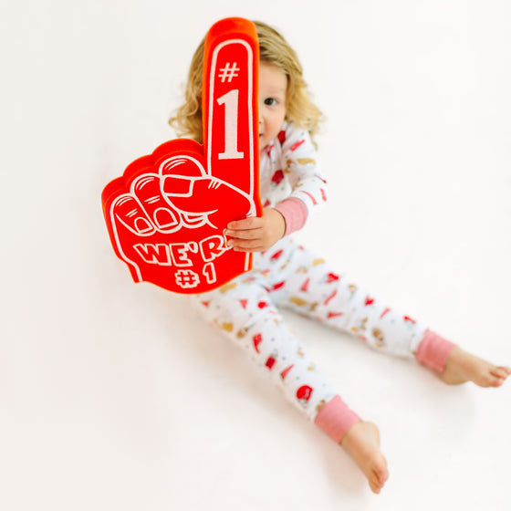 Child holding a red foam finger with '#1' on a white background