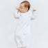 Baby in a white lap gown lying on a white surface
