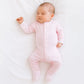 baby girl sleeping peacefully on white bed wearing a pima mini stripe footie in pink by magnolia baby.