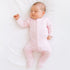 baby girl sleeping peacefully on white bed wearing a pima mini stripe footie in pink by magnolia baby.